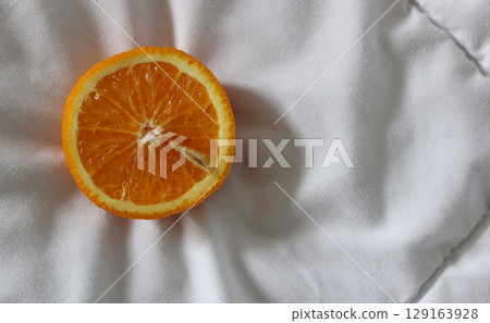 Cut in half fresh orange fruit on a quilted blanket at a side of image concept for logo or titles Cut in half fresh orange fruit on a quilted blanket at a side of image concept for logo or titles 129163928