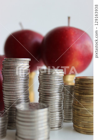 Defocused Fresh Apples And Piles Of Silvery And Brass Coins In A Columns Symbolizing Price Of Fruits Defocused Fresh Apples And Piles Of Silvery And Brass Coins In A Columns Symbolizing Price Of Fruits 129163938