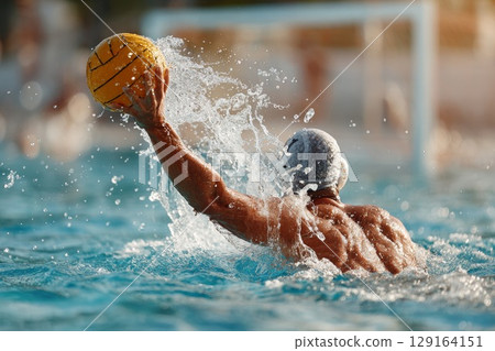 Male water polo player throwing ball in dynamic action during competitive match in pool 129164151