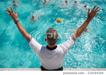 Water polo coach directing players in a vibrant swimming pool during an intense match Water polo coach directing players in a vibrant swimming pool during an intense match 129164164