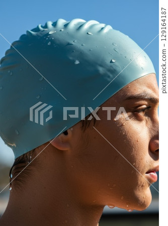 Young athlete wearing a blue swim cap, showcasing determination and focus before diving 129164187