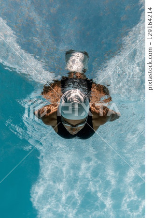 Diver gracefully gliding underwater, showcasing athleticism and fluid motion in a serene aquatic environment 129164214