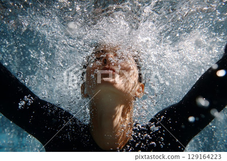 Diver emerging from water, showcasing graceful movement and dynamic splashes in aquatic environment Diver emerging from water, showcasing graceful movement and dynamic splashes in aquatic environment 129164223