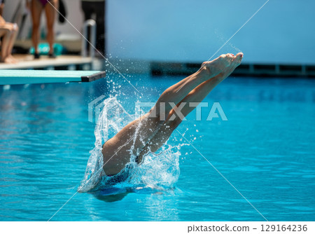 Diver executing a perfect entry into the water, showcasing skill and precision in springboard diving 129164236