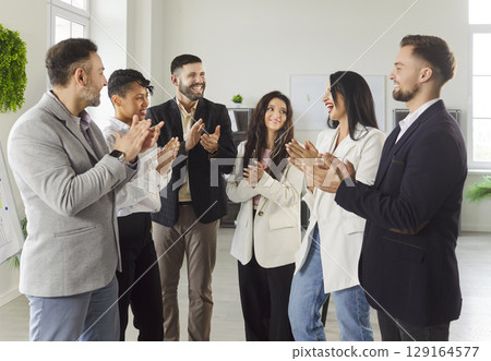 Group of multiethnic happy business people men and women standing in a circle and applauding. 129164577