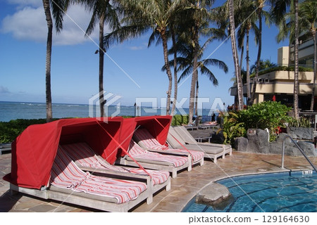 Red canopy chairs by the pool overlooking the ocean Red canopy chairs by the pool overlooking the ocean 129164630