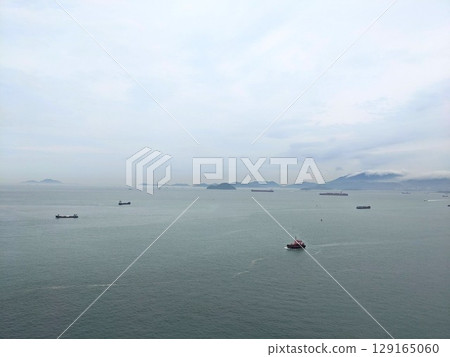 Aerial perspective of a tugboat and cargo ships in the vast South China Sea off Hong Kong 129165060