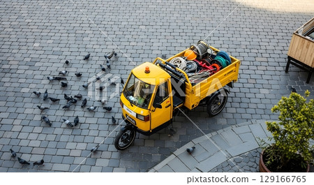 Aerial View of a Yellow Three Wheeled Vehicle Loaded With Luggage on Cobblestone Street 129166765