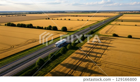 Aerial View Of Highway And Truck Through Golden Wheat Fields Under Blue Sky 129166800