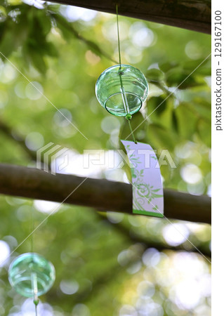Wind chimes swaying in the shade of the forest trees 129167100