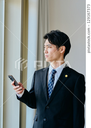 一位二十多歲的年輕律師正在操作智慧型手機 129167373