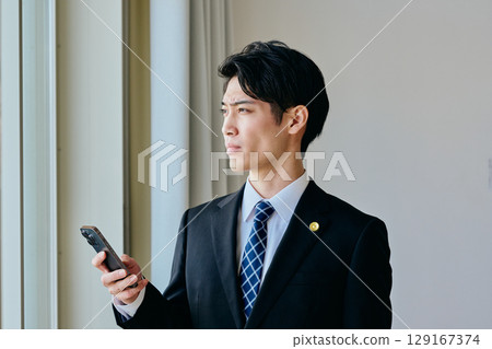 一位二十多歲的年輕律師正在操作智慧型手機 129167374