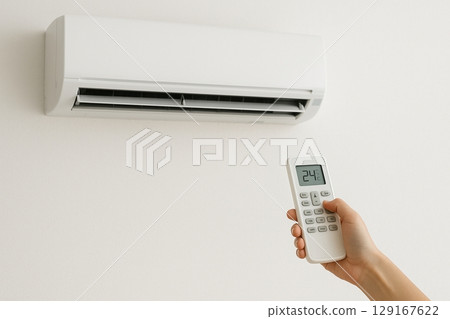 Hand holding and operating an air conditioner remote control Hand holding and operating an air conditioner remote control 129167622