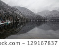 A serene winter lake surrounded by snow-covered trees 129167837