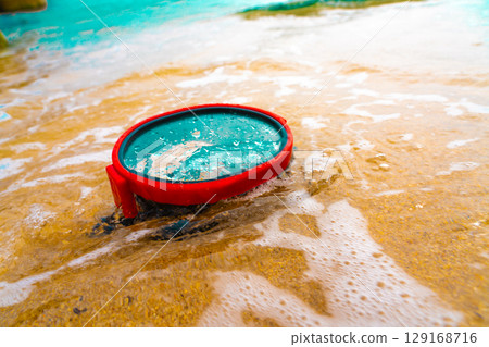 A diving mask lies on a sandy beach and is washed by waves of water 129168716