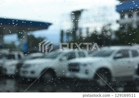 water drop on mirror in defocused car parking background 129169511