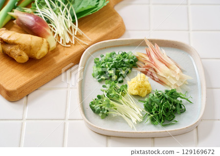 Assorted chopped condiments: ginger, myoga, shiso leaves, green onions, and daikon radish 129169672