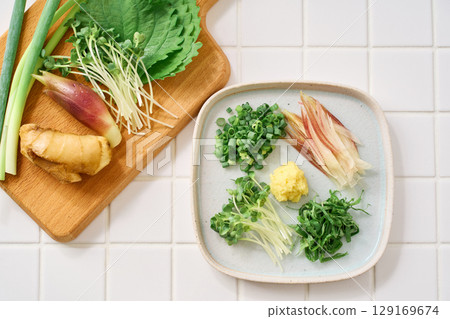 Assorted chopped condiments: ginger, myoga, shiso leaves, green onions, and daikon radish 129169674