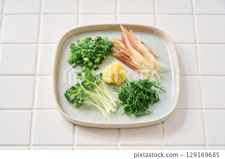 Assorted chopped condiments: ginger, myoga, shiso leaves, green onions, and daikon radish 129169685