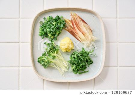 Assorted chopped condiments: ginger, myoga, shiso leaves, green onions, and daikon radish 129169687