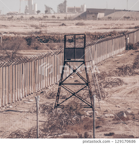 Fenced borderline, barbed wires and watchtower. Non-passable military zone. 129170686