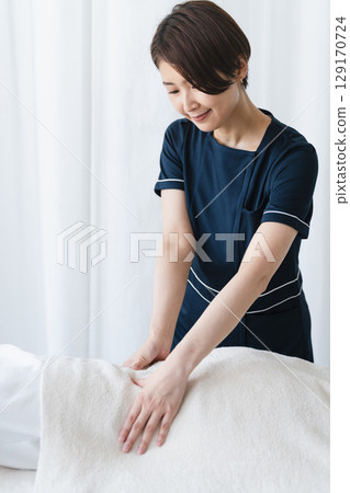 年輕女子接受治療師的按摩美容形象 年輕女子接受治療師的按摩美容形象 129170724