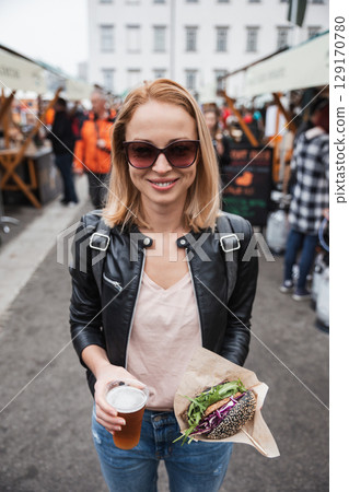 Beautiful young woman holding delicious organic salmon vegetarian burger and homebrewed IPA beer on open air beer an burger urban street food festival in Ljubljana, Slovenia Beautiful young woman holding delicious organic salmon vegetarian burger and homebrewed IPA beer on open air beer an burger urban street food festival in Ljubljana, Slovenia 129170780
