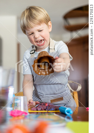 Blond boy sculpts from plasticine at home at the table. The idea and concept of the school, home education and developmental activities. 129170813