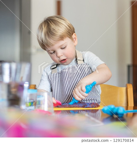 Blond boy sculpts from plasticine at home at the table. The idea and concept of the school, home education and developmental activities. 129170814
