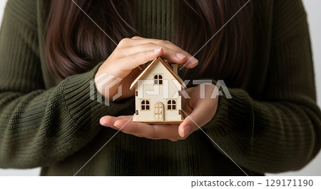 woman holding a model of house 129171190