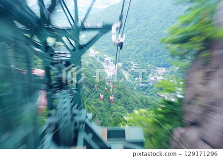 The moment when the gondola of the Gozaisho Ropeway in Mie Prefecture passes through the green support pillar, with Yunoyama Onsen visible below [July] 129171296