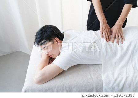 Young man receiving massage from chiropractor Young man receiving massage from chiropractor 129171395