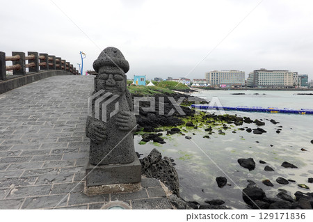 Jeju dol hareubang stone statue standing guard by the sea symbolizing protection and cultural heritage of the island Jeju dol hareubang stone statue standing guard by the sea symbolizing protection and cultural heritage of the island 129171836