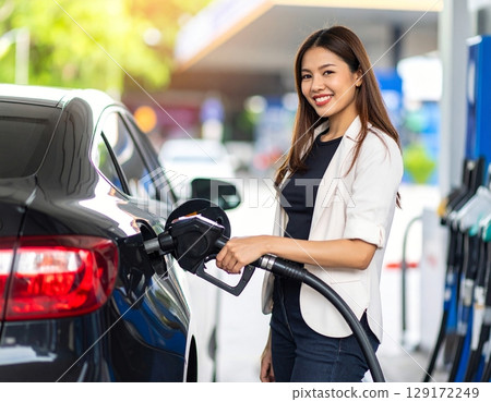 Woman refueling at a gas station 129172249