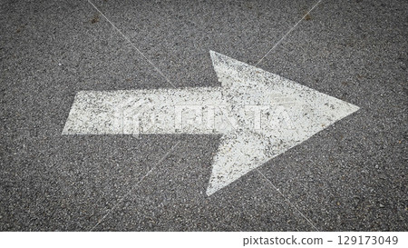 White painted arrow on asphalt road surface, representing direction and navigation in transportation contexts. 129173049