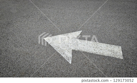 White painted arrow on asphalt road surface, representing direction and navigation in transportation contexts. White painted arrow on asphalt road surface, representing direction and navigation in transportation contexts. 129173052