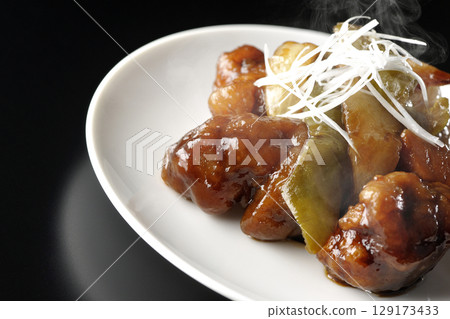 Hot sweet and sour pork with black vinegar photographed against a black background 129173433