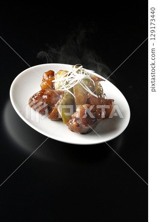 Hot sweet and sour pork with black vinegar photographed against a black background 129173440