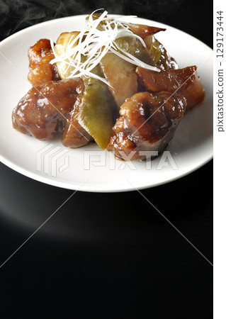 Hot sweet and sour pork with black vinegar photographed against a black background 129173444