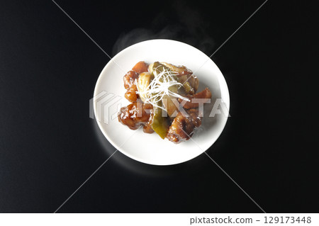 Hot sweet and sour pork with black vinegar photographed against a black background 129173448