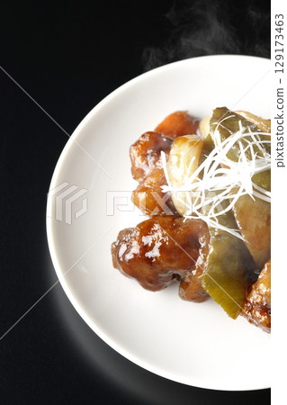 Hot sweet and sour pork with black vinegar photographed against a black background Hot sweet and sour pork with black vinegar photographed against a black background 129173463
