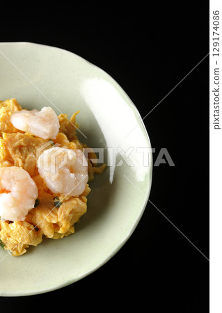 Chinese stir-fried shrimp and eggs photographed against a black background Chinese stir-fried shrimp and eggs photographed against a black background 129174086