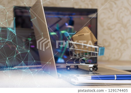 Mini shopping cart with parcels on laptop, network connections overlayed, symbolizing modern ecommerce, logistics and digital retail innovation. 129174405