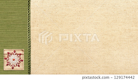 Horizontal Christmas background with beige and green canvas texture and felt snowflake. Holiday backdrop for scrapbooking with linen fabric texture and decorative snowflake. Copy space for text 129174442