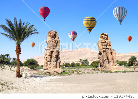 Tourist attraction balloon flight in Valley of Kings, Luxor, Egypt. Air balloons over the Colossi of Memnon in Theban Necropolis, Egypt. Topic of travel, trip abroad on vacation, cruises and tours Tourist attraction balloon flight in Valley of Kings, Luxor, Egypt. Air balloons over the Colossi of Memnon in Theban Necropolis, Egypt. Topic of travel, trip abroad on vacation, cruises and tours 129174453