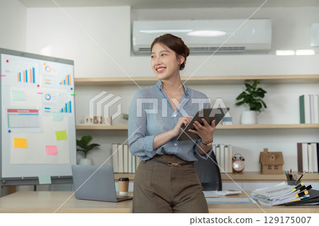 Cheerful woman with tablet in modern office 129175007