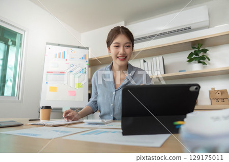 Remote Work. Happy woman engaging with tablet and reviewing data in modern office. Remote Work. Happy woman engaging with tablet and reviewing data in modern office. 129175011