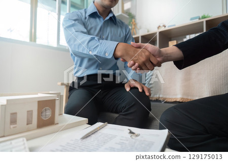 Business Partnership. Two professionals shaking hands in an office setting. 129175013