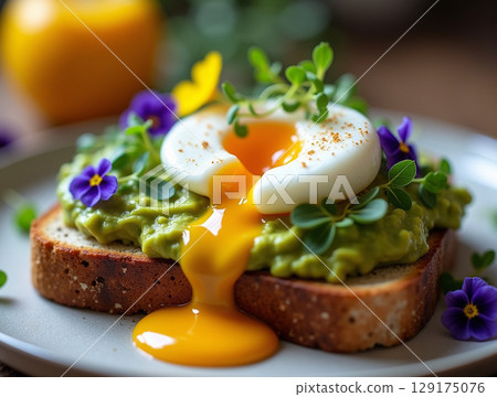 Artisan Sourdough Toast with Smashed Avocado and a Poached Egg with Dripping Yolk 129175076