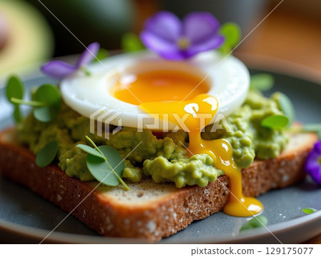 Elegant Avocado Toast with Poached Egg, Edible Flowers and Microgreens 129175077